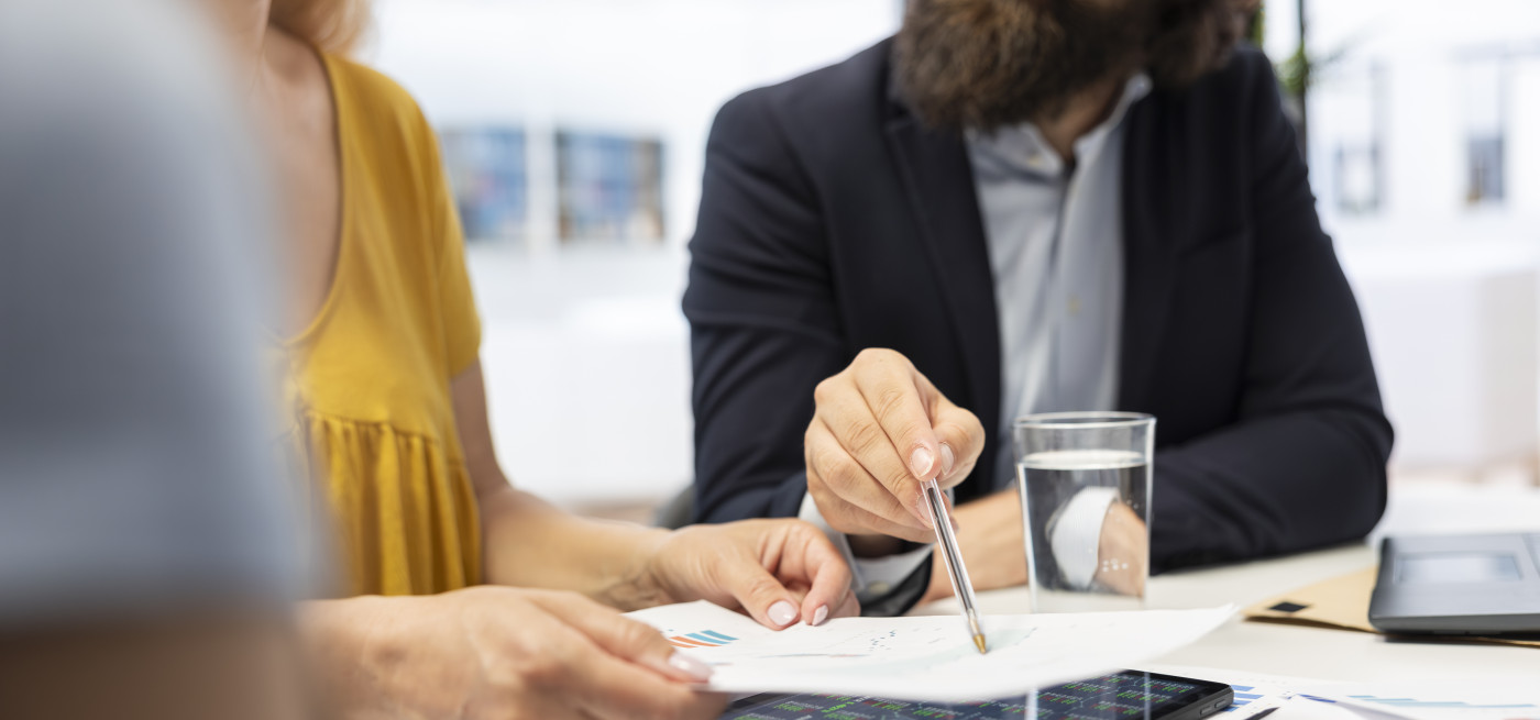 Casal a analisar despesas em casa com documentos e portátil, representando a revisão do crédito habitação para reduzir a prestação mensal.